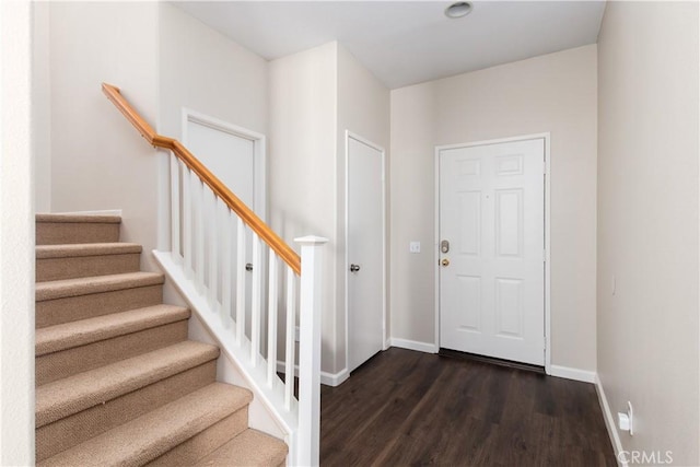 entrance foyer with dark wood-type flooring, stairway, and baseboards