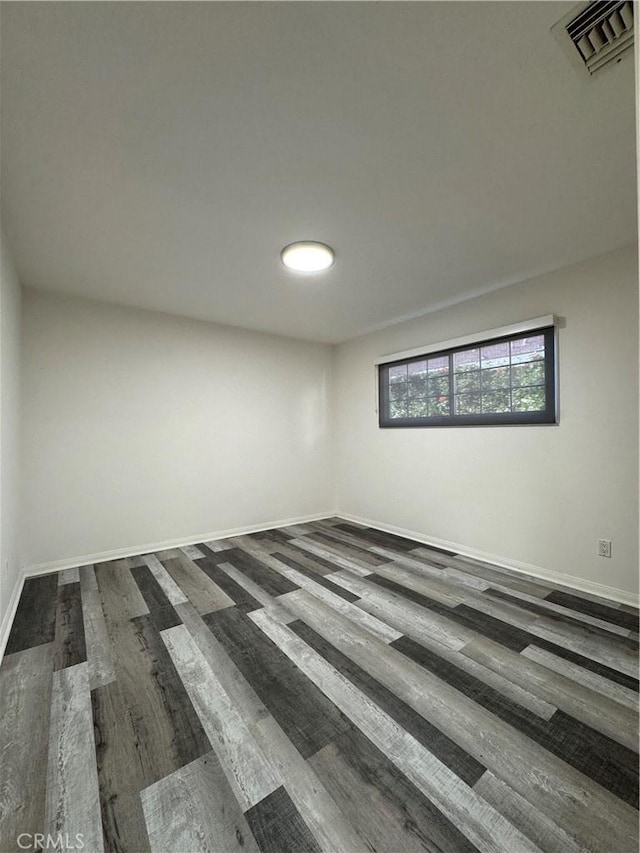 unfurnished room with dark wood-type flooring, visible vents, and baseboards