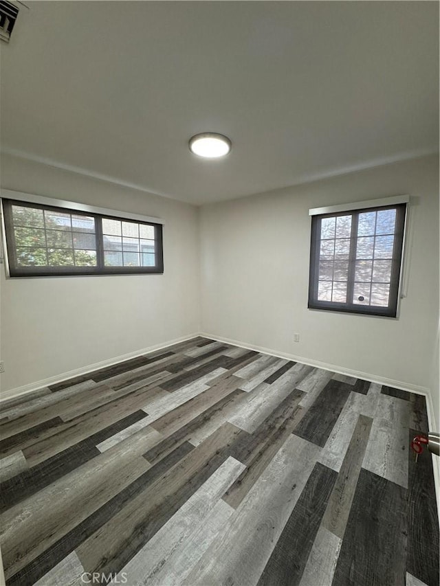 empty room with visible vents, baseboards, and wood finished floors