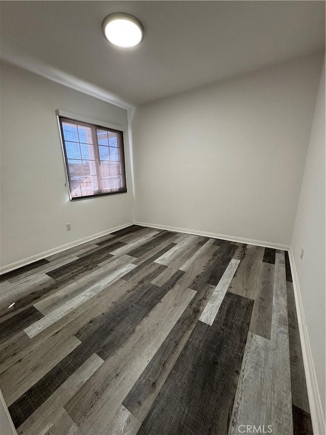 unfurnished room with dark wood-style flooring and baseboards