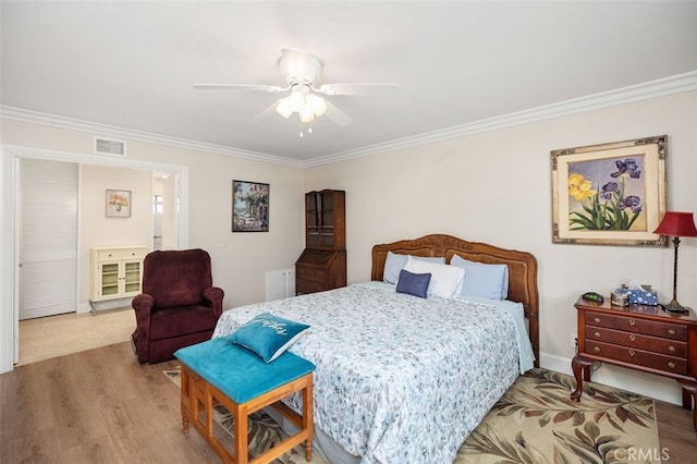 bedroom with ornamental molding, a ceiling fan, visible vents, and wood finished floors