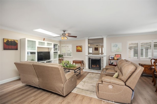 living room with light wood-type flooring, a wealth of natural light, and a lit fireplace