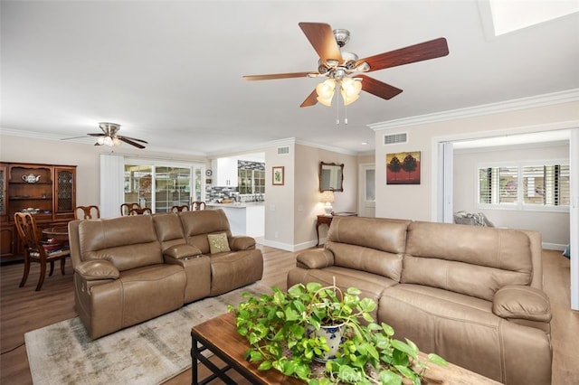 living area with a ceiling fan, crown molding, visible vents, and wood finished floors