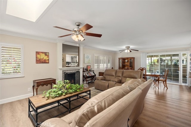 living area with crown molding, a fireplace, a wealth of natural light, and wood finished floors