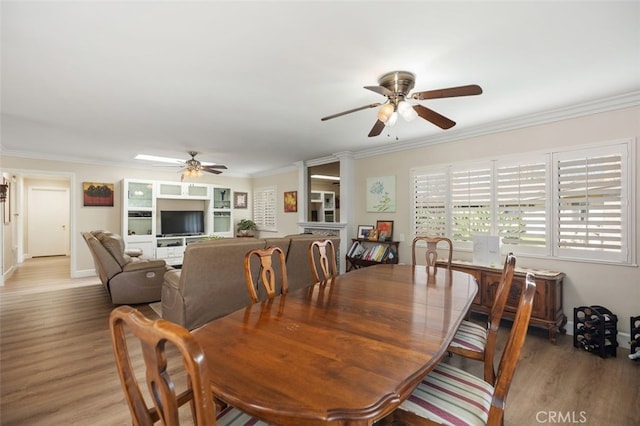 dining area with ornamental molding, ceiling fan, baseboards, and wood finished floors