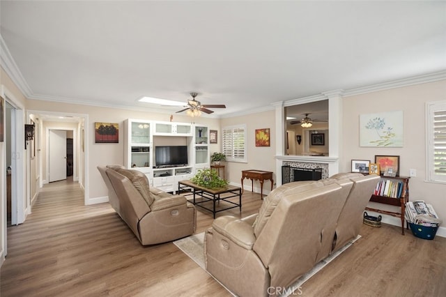 living area featuring light wood-style flooring, a fireplace, ornamental molding, and a wealth of natural light