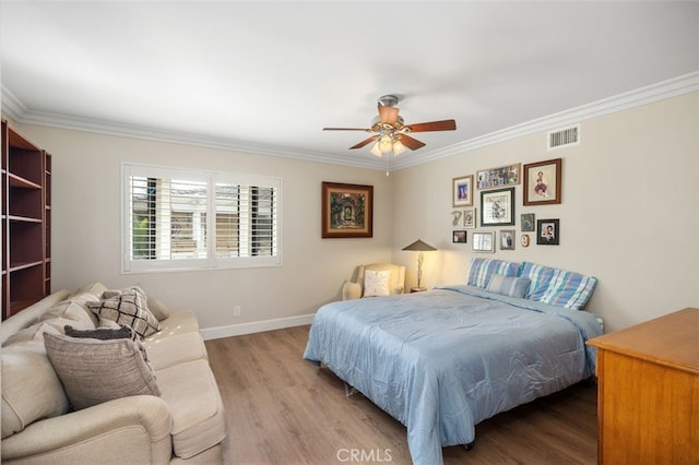 bedroom with wood finished floors, a ceiling fan, visible vents, baseboards, and ornamental molding