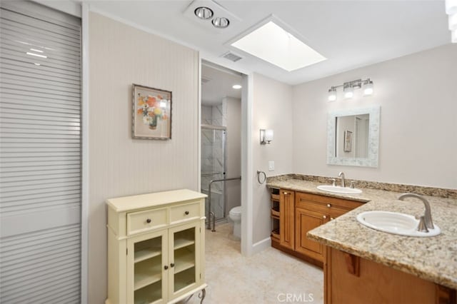 bathroom with double vanity, a sink, toilet, and a shower stall