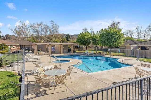 pool featuring a patio area, a hot tub, fence, and a mountain view