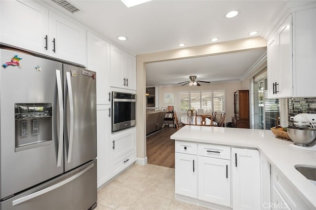 kitchen featuring appliances with stainless steel finishes, light countertops, white cabinetry, and a peninsula