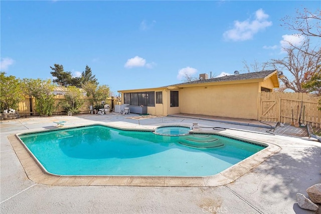 view of pool with a patio, a sunroom, a fenced backyard, a gate, and a pool with connected hot tub