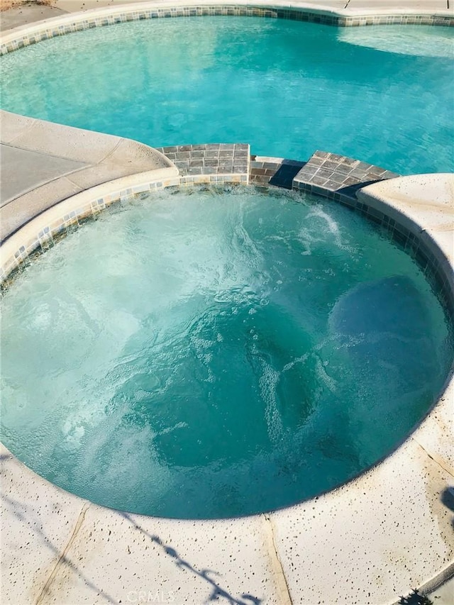 view of swimming pool with a pool with connected hot tub