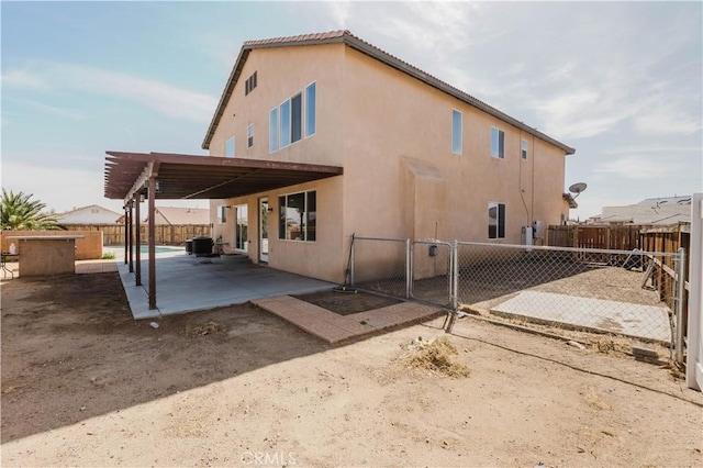 back of house featuring central AC unit, a patio, a fenced backyard, a gate, and stucco siding