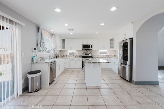 kitchen featuring glass insert cabinets, visible vents, appliances with stainless steel finishes, and a sink