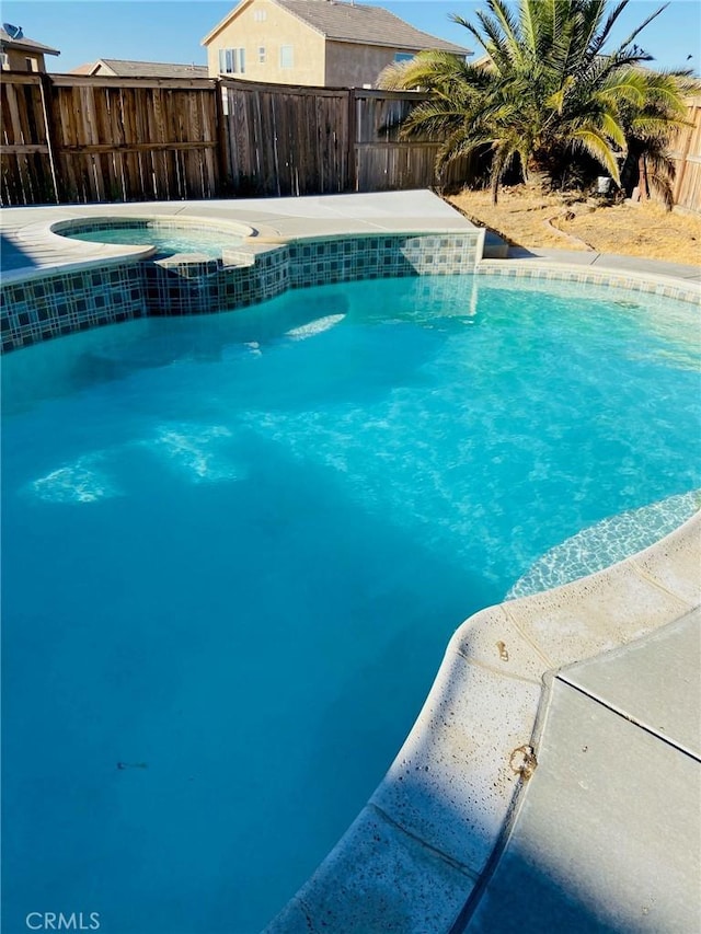 view of pool with a fenced in pool, fence, and an in ground hot tub