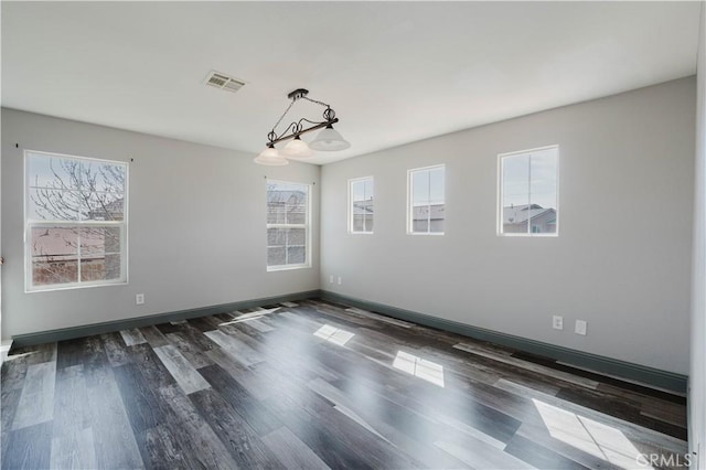 spare room featuring dark wood-style floors, baseboards, visible vents, and a healthy amount of sunlight