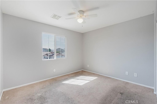 carpeted spare room featuring a ceiling fan, visible vents, and baseboards