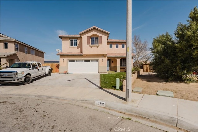 mediterranean / spanish home with a tile roof, stucco siding, an attached garage, fence, and driveway