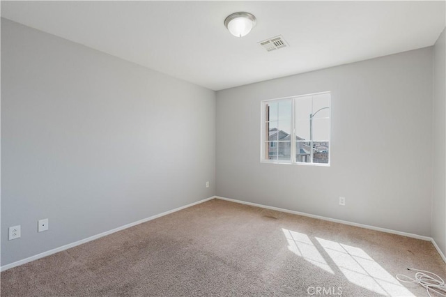 spare room with carpet floors, visible vents, and baseboards