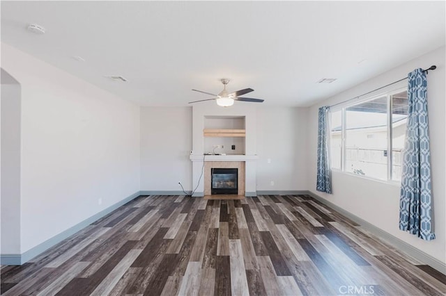 unfurnished living room with visible vents, baseboards, a tiled fireplace, ceiling fan, and wood finished floors