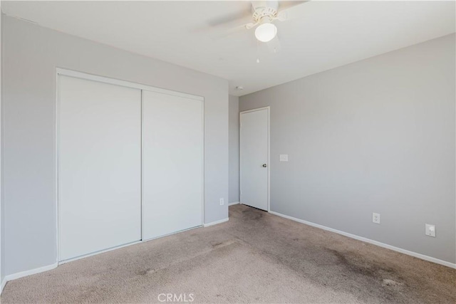 unfurnished bedroom featuring a closet, carpet flooring, a ceiling fan, and baseboards