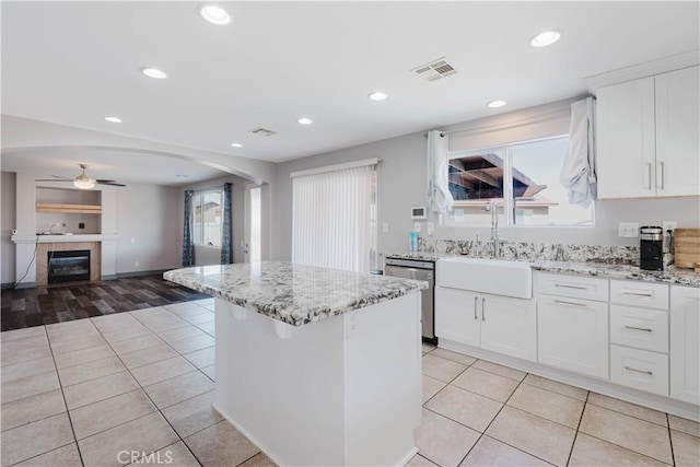 kitchen featuring arched walkways, stainless steel dishwasher, light tile patterned floors, and visible vents