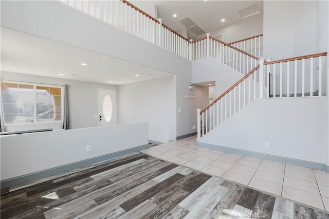 interior space with baseboards, wood finished floors, stairs, a high ceiling, and recessed lighting