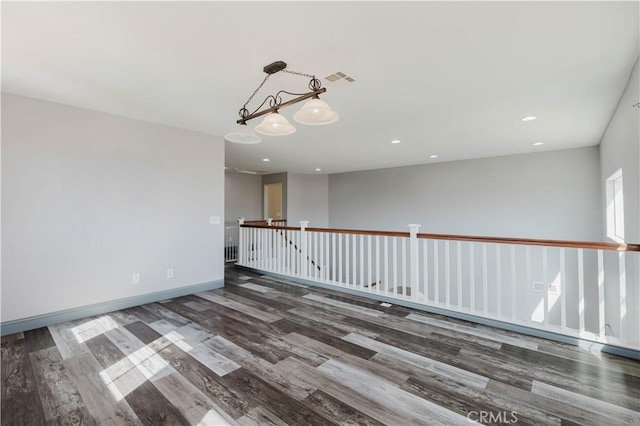 unfurnished room featuring recessed lighting, an inviting chandelier, baseboards, and wood finished floors