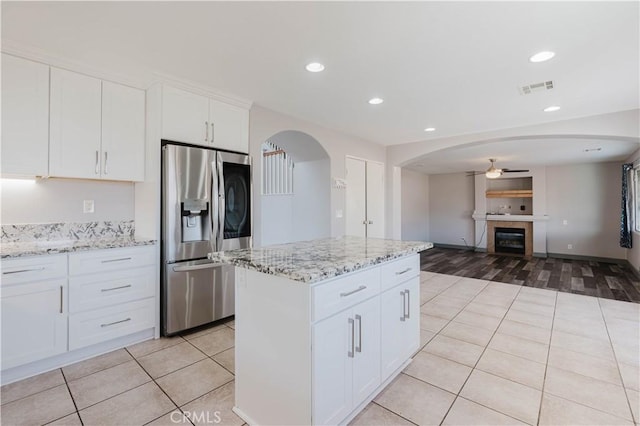 kitchen featuring light tile patterned floors, stainless steel fridge, visible vents, a tile fireplace, and ceiling fan