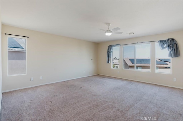 carpeted empty room featuring baseboards, visible vents, and a ceiling fan