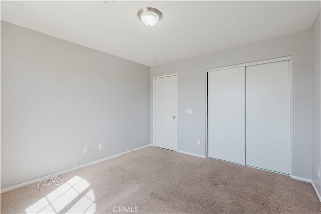 unfurnished bedroom featuring carpet floors, a closet, and baseboards