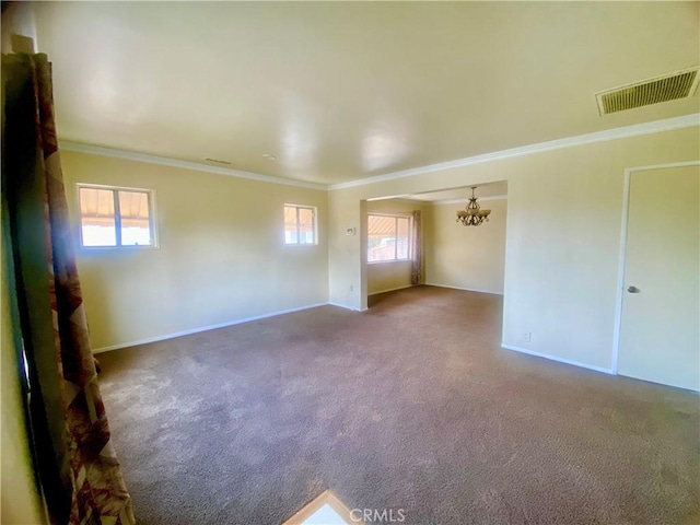 carpeted empty room featuring ornamental molding, a wealth of natural light, and visible vents