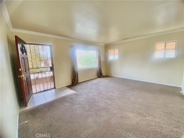 carpeted spare room featuring tile patterned flooring, baseboards, and ornamental molding