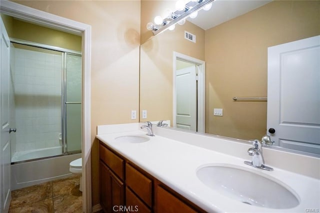 full bathroom with toilet, double vanity, a sink, and visible vents