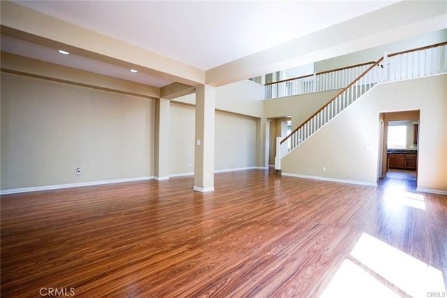 unfurnished living room with recessed lighting, stairway, baseboards, and wood finished floors