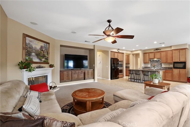 living room featuring light carpet, visible vents, baseboards, a glass covered fireplace, and recessed lighting