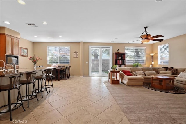 living area featuring light tile patterned floors, a ceiling fan, visible vents, and recessed lighting