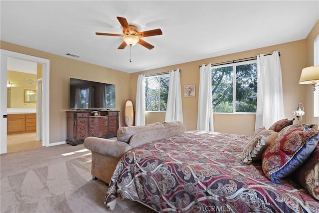 carpeted bedroom featuring ensuite bath, baseboards, visible vents, and a ceiling fan