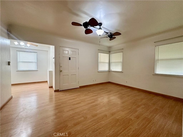 spare room featuring baseboards, ceiling fan, and light wood finished floors