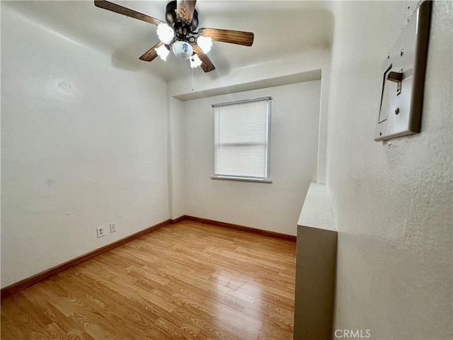 spare room featuring light wood finished floors, ceiling fan, and baseboards