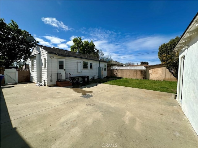 rear view of property featuring a patio, fence, and a gate