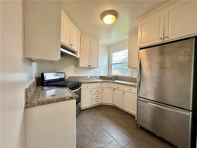 kitchen featuring stainless steel appliances, tile patterned flooring, a sink, and white cabinets