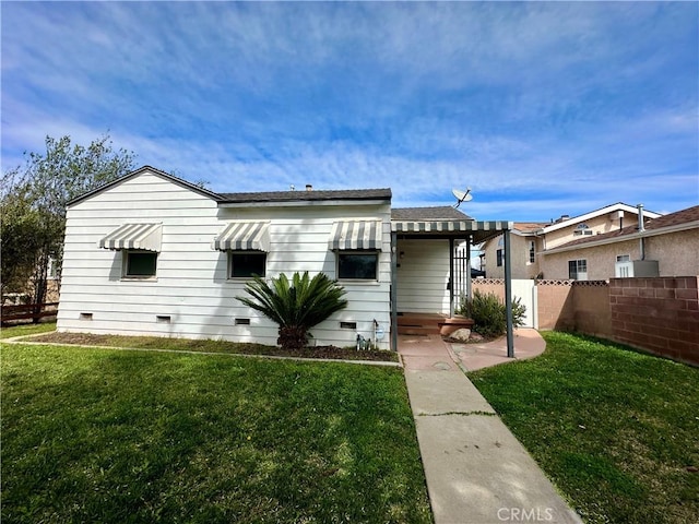 back of property with crawl space, fence, and a yard