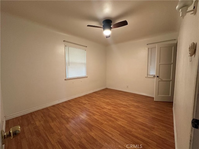 spare room featuring wood finished floors, a ceiling fan, and baseboards