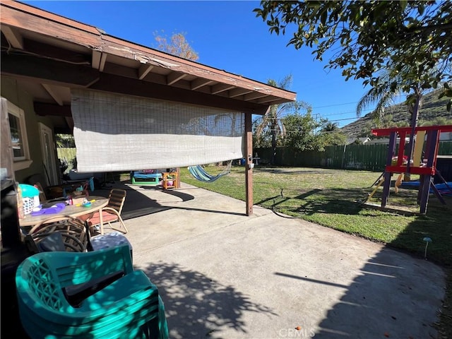 view of patio featuring a playground and fence