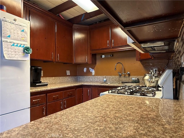 kitchen with beam ceiling, freestanding refrigerator, wood ceiling, gas stove, and a sink