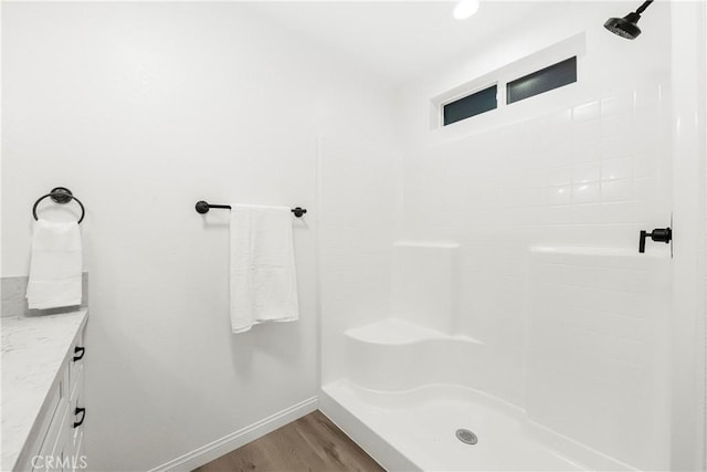 full bath with a shower, wood finished floors, vanity, and baseboards