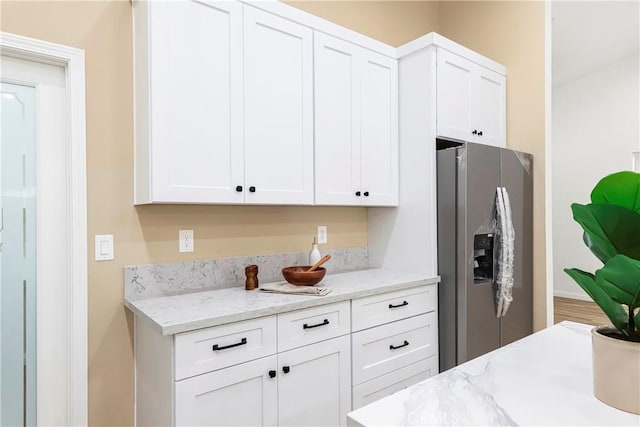 kitchen with white cabinets, light stone countertops, and stainless steel refrigerator with ice dispenser