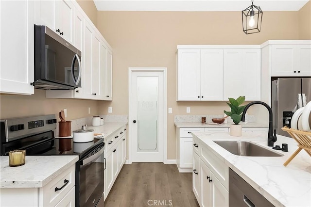 kitchen featuring appliances with stainless steel finishes, white cabinetry, a sink, and wood finished floors