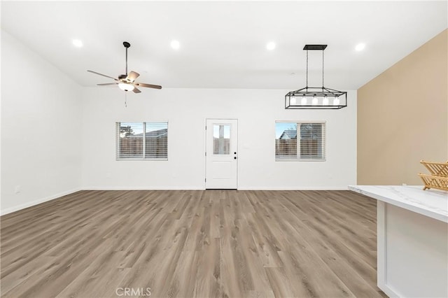 unfurnished living room featuring light wood-style flooring, baseboards, a ceiling fan, and recessed lighting